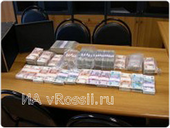 Пачки изъятых денег занимают почти весь стол.